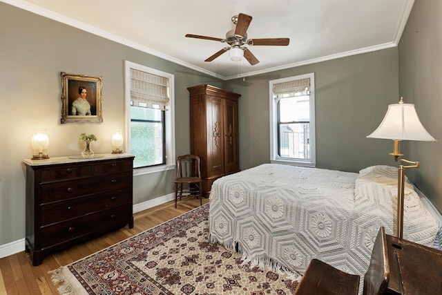 bedroom featuring wood finished floors, crown molding, baseboards, and a ceiling fan