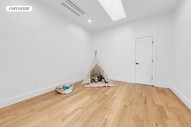 recreation room featuring visible vents, a skylight, baseboards, and wood finished floors