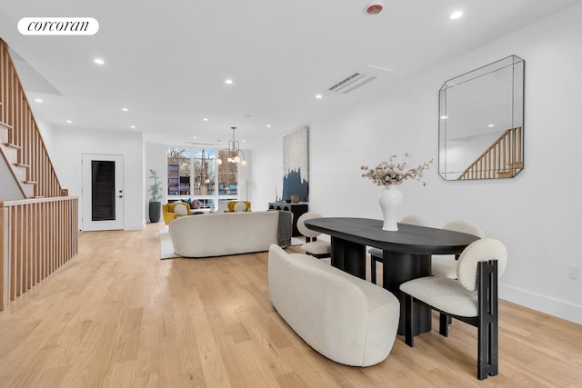 dining area featuring light wood finished floors, stairway, a chandelier, and visible vents