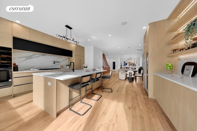 kitchen with visible vents, a breakfast bar area, light wood-type flooring, decorative backsplash, and modern cabinets