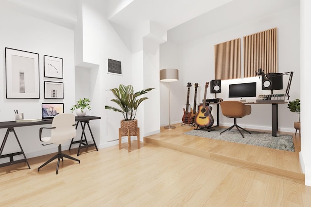 home office featuring wood finished floors, baseboards, and a towering ceiling