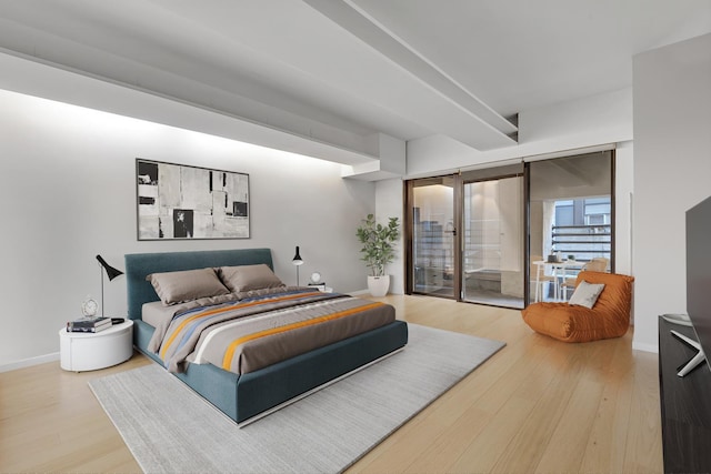 bedroom featuring access to exterior, wood finished floors, and baseboards