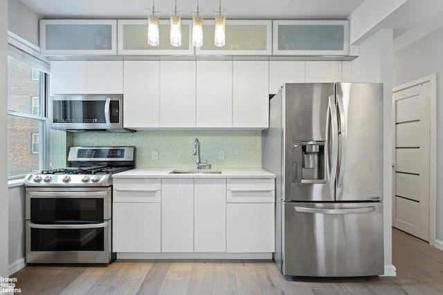 550 Grand St Unit H5G, New York City, NY 10002 - kitchen with appliances with stainless steel finishes, a sink, light countertops, white cabinets, and backsplash