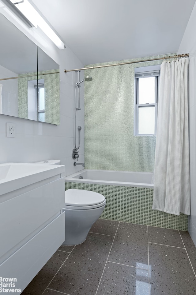 bathroom with tiled shower / bath, toilet, tile walls, and vanity