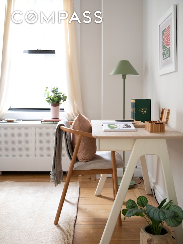 home office featuring wood finished floors and radiator heating unit