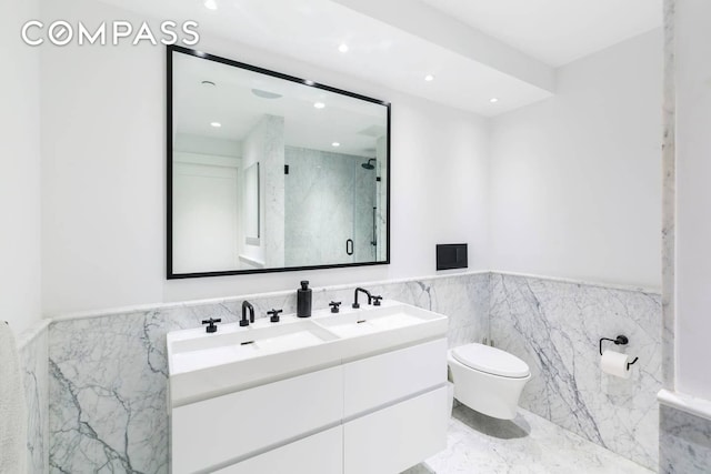 bathroom with toilet, marble finish floor, wainscoting, a marble finish shower, and double vanity