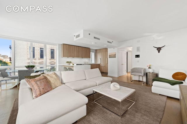 living room featuring a wall of windows, light wood-style flooring, and visible vents