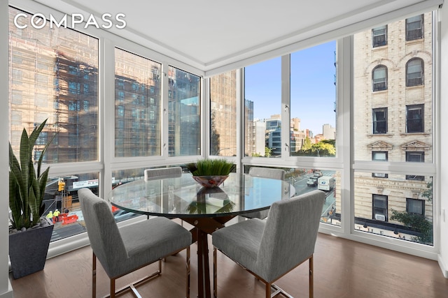 sunroom / solarium featuring a city view, wood finished floors, and expansive windows
