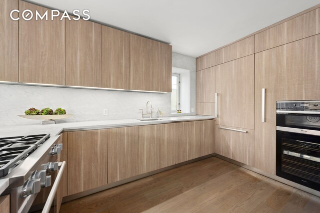 kitchen with stainless steel oven, modern cabinets, light countertops, and a sink