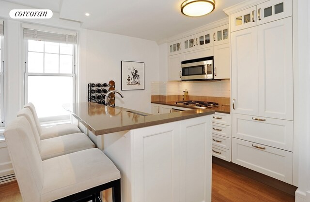 kitchen with dark countertops, a breakfast bar area, decorative backsplash, appliances with stainless steel finishes, and a sink