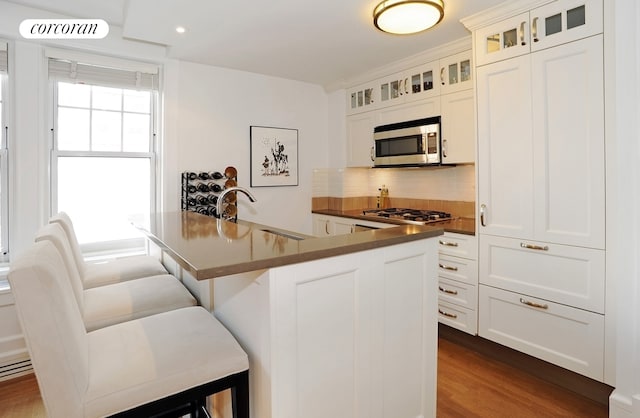 kitchen featuring stainless steel appliances, a sink, dark countertops, tasteful backsplash, and a breakfast bar area