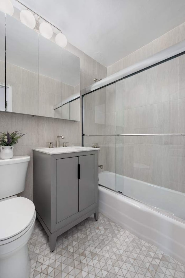 full bath with vanity, toilet, and combined bath / shower with glass door