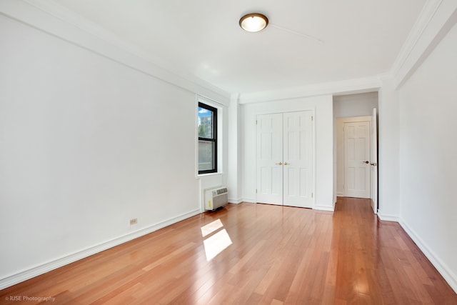 unfurnished bedroom with a closet, baseboards, light wood-style floors, and ornamental molding