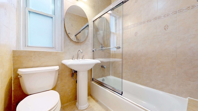 full bathroom with toilet, a sink, tile walls, tile patterned flooring, and enclosed tub / shower combo