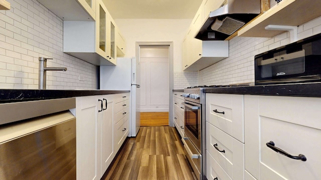 kitchen with stainless steel range with gas stovetop, freestanding refrigerator, dark wood-type flooring, under cabinet range hood, and dark countertops