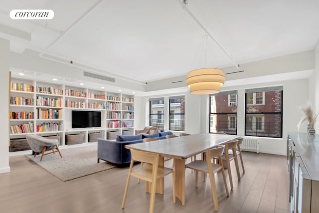 dining space featuring visible vents, radiator heating unit, and wood finished floors