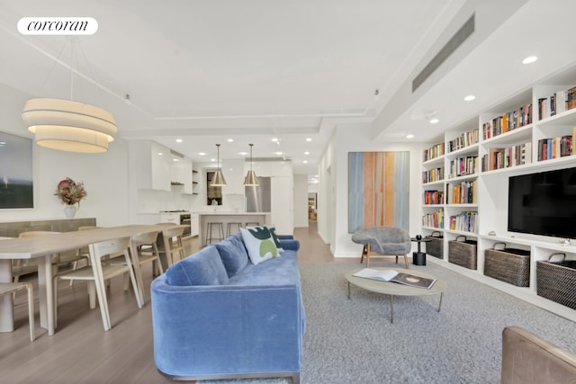 living room featuring built in features, recessed lighting, visible vents, and light wood-type flooring