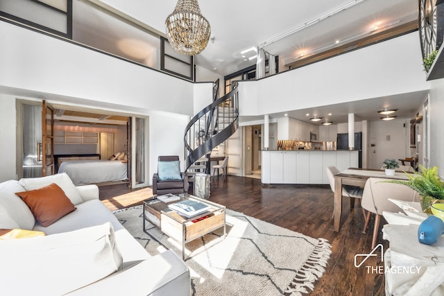 living room with a chandelier, stairway, a high ceiling, and wood finished floors