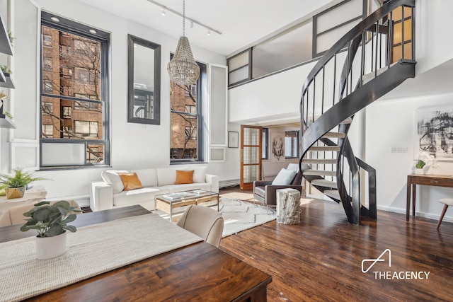 interior space with wood finished floors, a high ceiling, stairs, rail lighting, and a chandelier