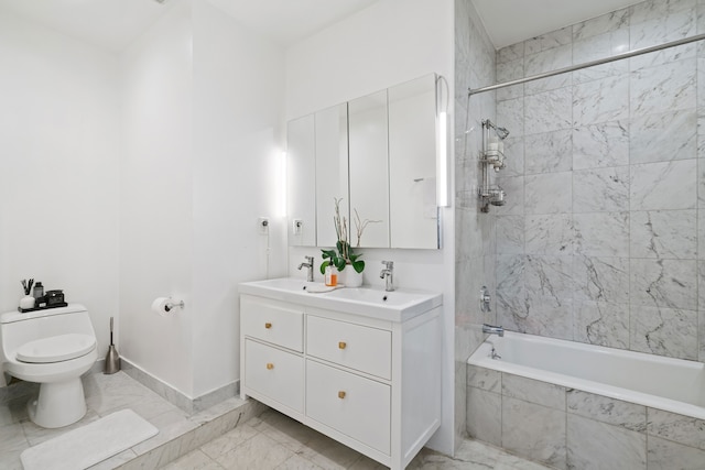 full bathroom with marble finish floor, toilet, tiled shower / bath combo, and a sink