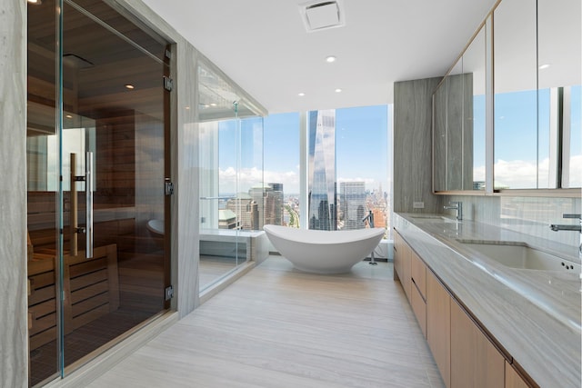 full bath featuring a freestanding bath, double vanity, a view of city, and a sink