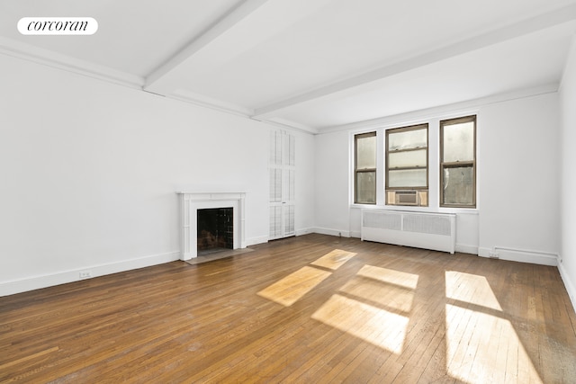 71 Park Ave Unit 3C, New York City, NY 10016 - unfurnished living room featuring radiator, a fireplace with flush hearth, hardwood / wood-style floors, baseboards, and beam ceiling