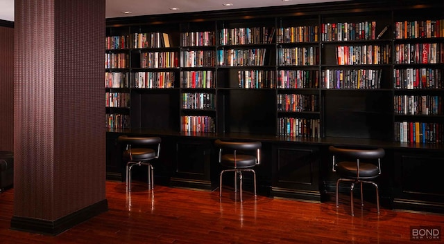 bar with built in desk and wood finished floors