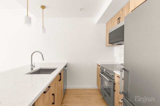 kitchen with hanging light fixtures, stainless steel refrigerator, light wood-style floors, light countertops, and tasteful backsplash