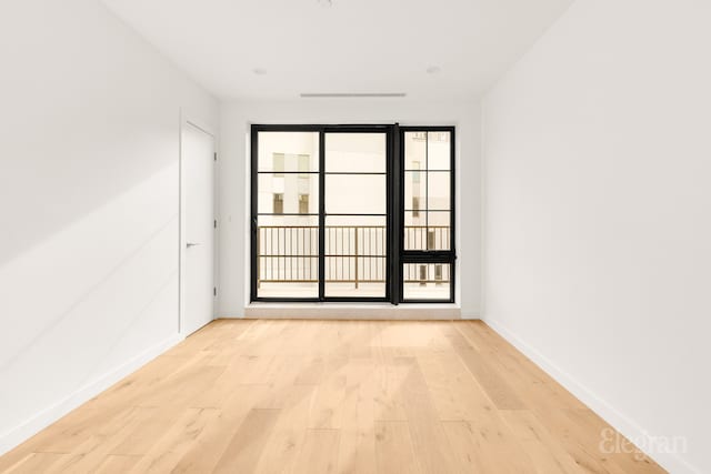 spare room featuring light wood-type flooring and baseboards