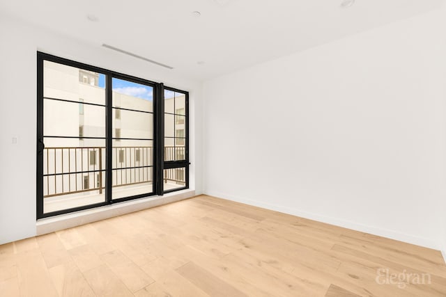 spare room featuring baseboards and light wood finished floors