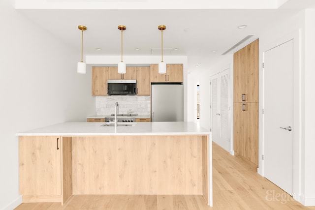 kitchen with stainless steel fridge, light countertops, light wood-style floors, and backsplash