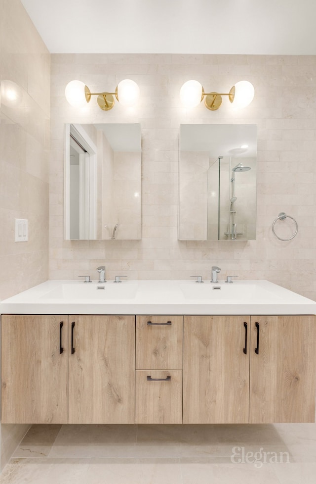 full bath with double vanity, a sink, and tile walls