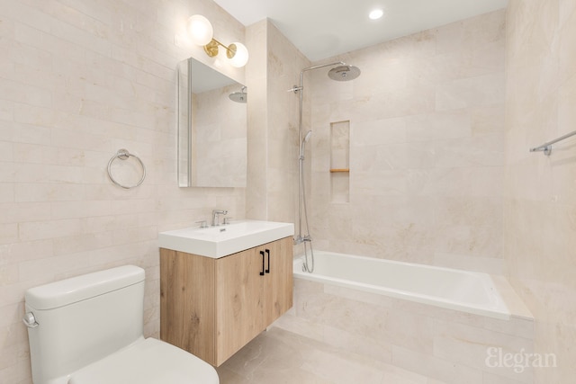 bathroom featuring tiled shower / bath combo, toilet, tile walls, and vanity