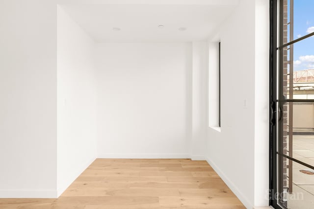 spare room with baseboards and light wood finished floors