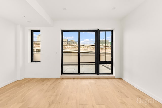 unfurnished room featuring a healthy amount of sunlight, light wood-type flooring, and baseboards