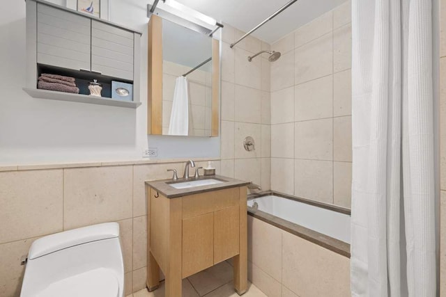 bathroom with toilet, tiled shower / bath combo, vanity, and tile walls