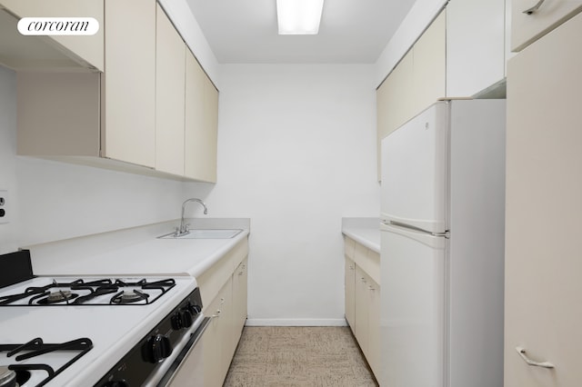 kitchen featuring visible vents, a sink, white appliances, light countertops, and baseboards