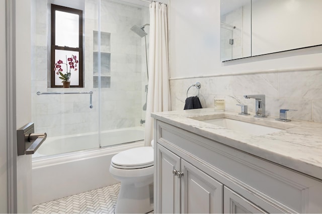 full bath with combined bath / shower with glass door, toilet, tile walls, and vanity