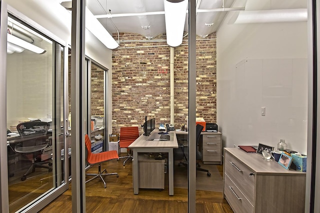 home office featuring brick wall and dark wood-type flooring