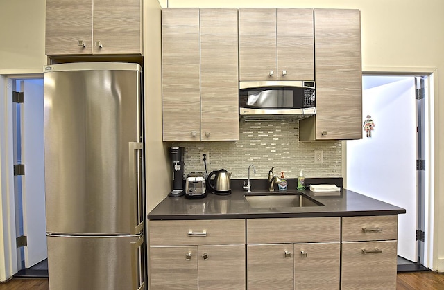 kitchen featuring dark countertops, tasteful backsplash, dark wood-type flooring, stainless steel appliances, and a sink