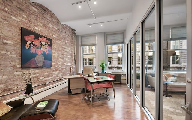 office featuring brick wall, rail lighting, and wood finished floors