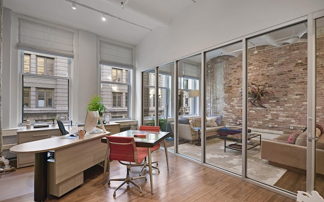 11 W 20th St Unit 4-Flr, New York City, NY 10011 - home office with light wood-type flooring, track lighting, a high ceiling, and brick wall