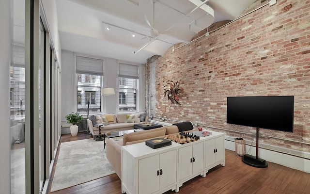 living room featuring rail lighting, hardwood / wood-style floors, and brick wall