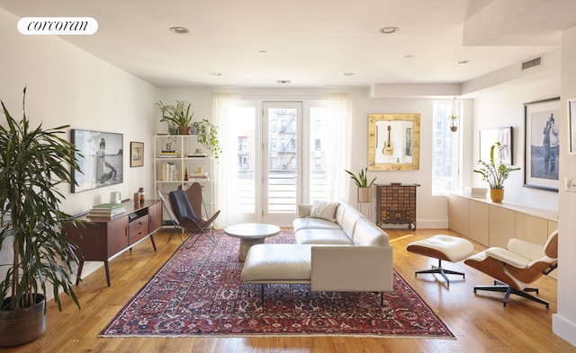 living area with recessed lighting, visible vents, baseboards, and wood finished floors