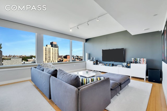 living room featuring light wood-style flooring, rail lighting, and baseboards