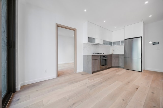 kitchen with white cabinets, appliances with stainless steel finishes, modern cabinets, and light wood-type flooring