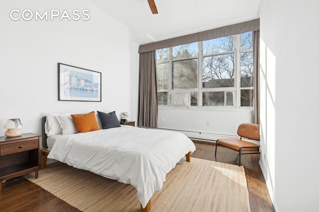 bedroom featuring a baseboard radiator, wood finished floors, and a ceiling fan