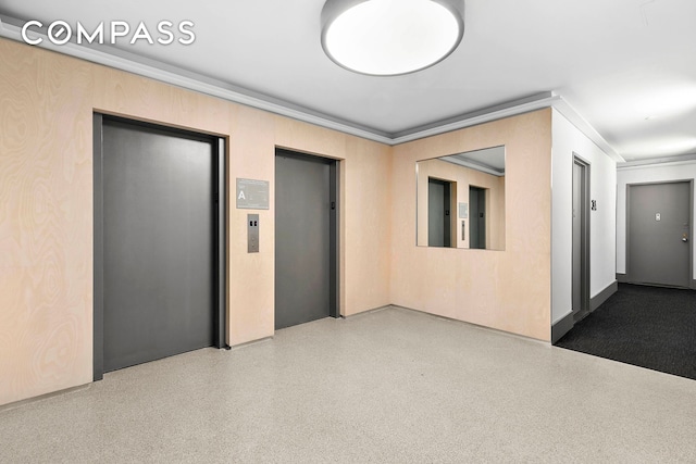 empty room featuring elevator, crown molding, and speckle patterned floor