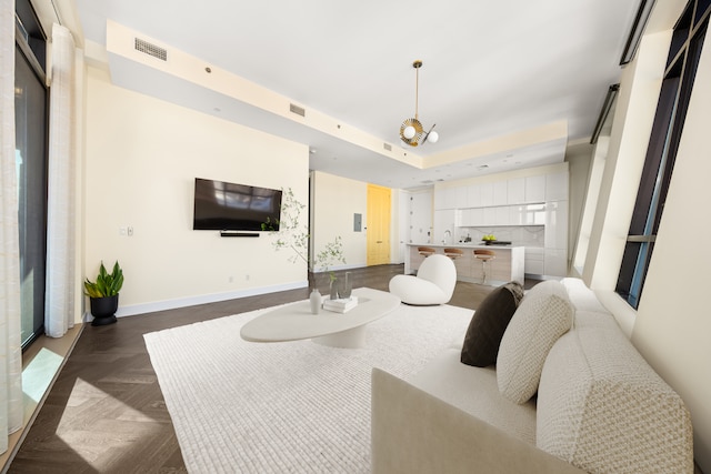 living room featuring visible vents, baseboards, and a raised ceiling