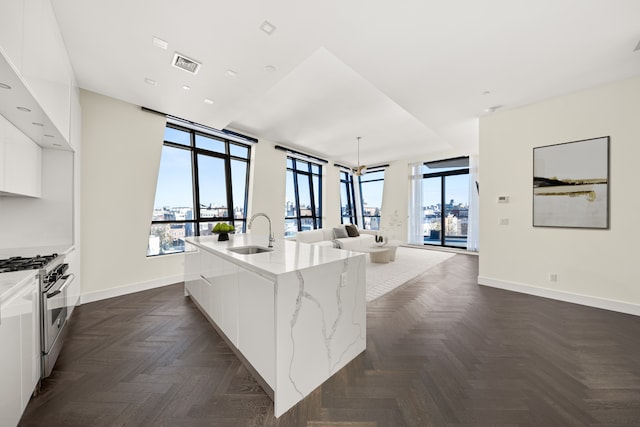 kitchen with high end stove, modern cabinets, a healthy amount of sunlight, and a sink